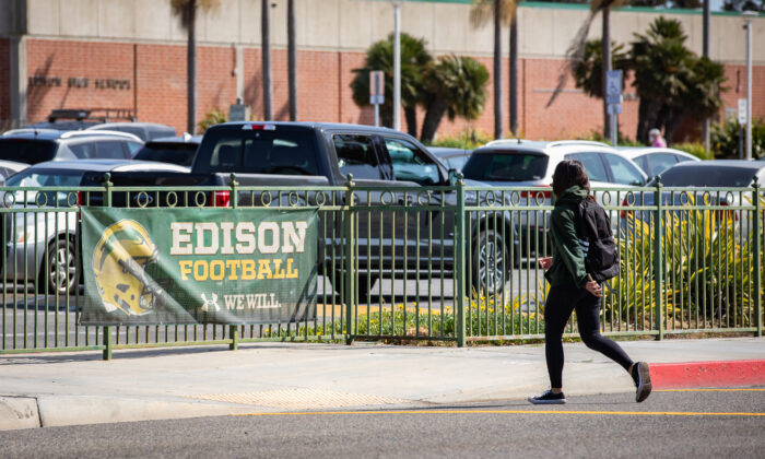 A student walks past a sign for the school's football team at Edison Highschool in Huntington Beach, Calif., on March 10, 2022. (John Fredricks/The Epoch Times)
