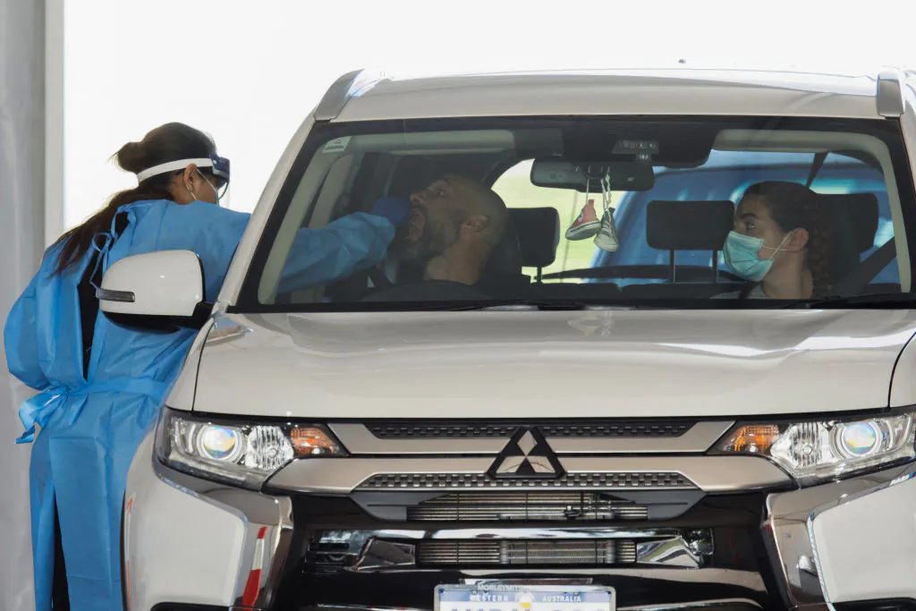 A healthcare worker takes a swab from a patient at a drive-through testing station in Perth, Australia on Jun. 29, 2021. (Photo by TREVOR COLLENS/AFP via Getty Images)
