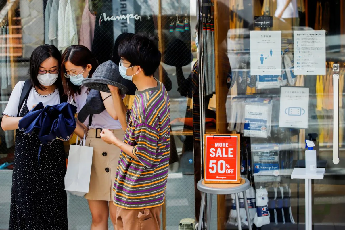 People wearing masks stand outside a shop in Harajuku shopping area in Tokyo on Aug. 9, 2021. (Androniki Christodoulou/Reuters)