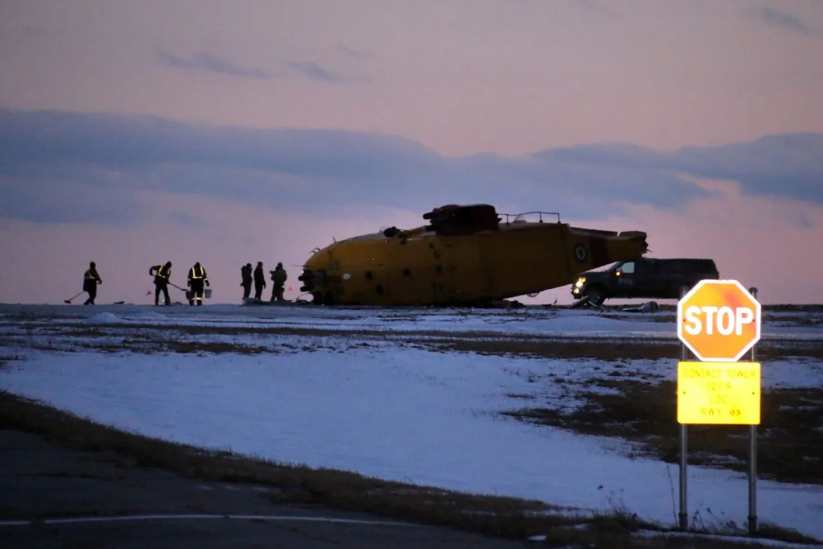 Emergency crews work around a CH-149 Cormorant search and rescue helicopter that crashed at 9 Wing Canadian Forces Base Gander, in Gander, N.L., March 10, 2022. (The Canadian Press/Scott Cook)