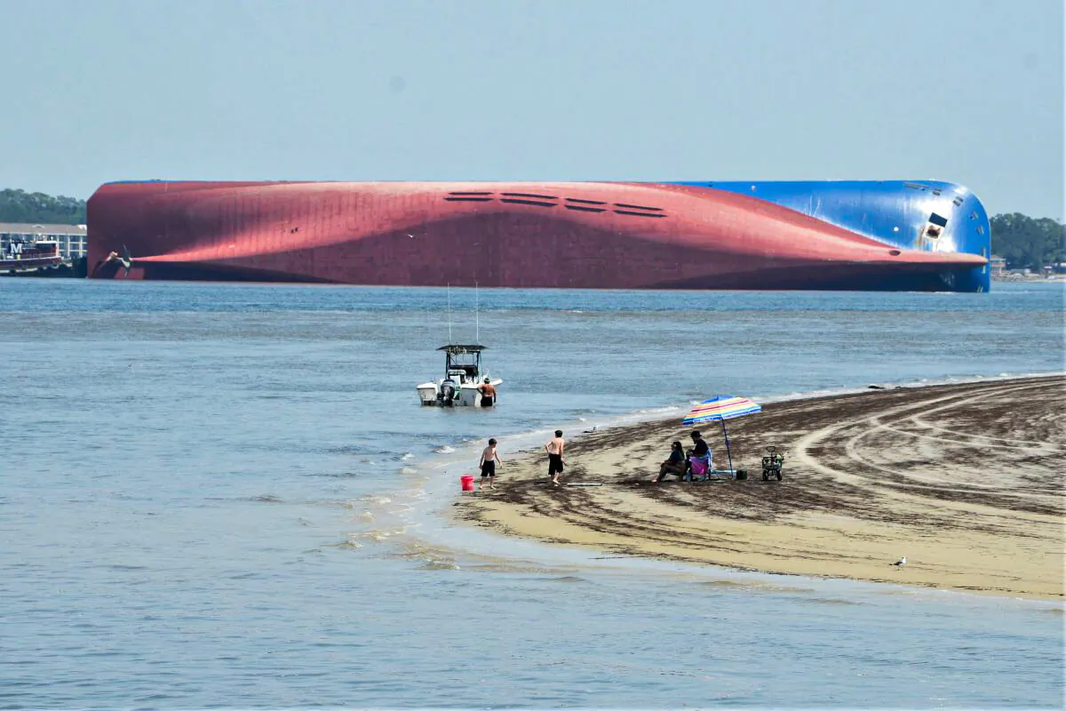 People are shown on Jekyll Island's Driftwood Beach as the Golden Ray cargo ship is capsized in the background, off the Georgia coast, on Sept. 8, 2019. (Terry Dickson/AP Photo)