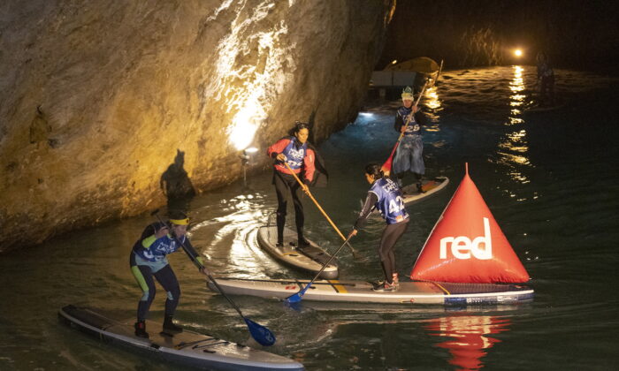 Competitors paddle during the BAT race, a Stand Up Paddle (SUP) race of the Alpine Lakes Tour, on Europe's biggest underground lake, in St-Leonard near Sion, Switzerland, on March 12, 2022. (Denis Balibouse/Reuters)