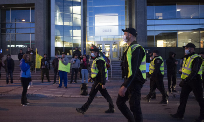 Police officers walk toward demonstrators protesting against curfew measures in front of Quebec Deputy Premier and Public Security Minister Genevieve Guilbault's office in Quebec City on April 13, 2021. (Jacques Boissinot/The Canadian Press)