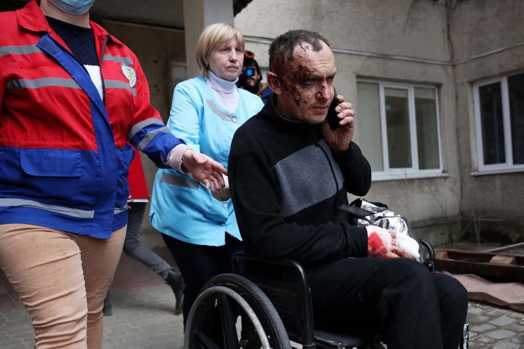 A man wounded in this morning's air strikes at a nearby military complex is assisted by medical staff outside Novoiavorivsk District Hospital on March 13, 2022 in Novoiavorivsk, Ukraine. (Dan Kitwood/Getty Images)
