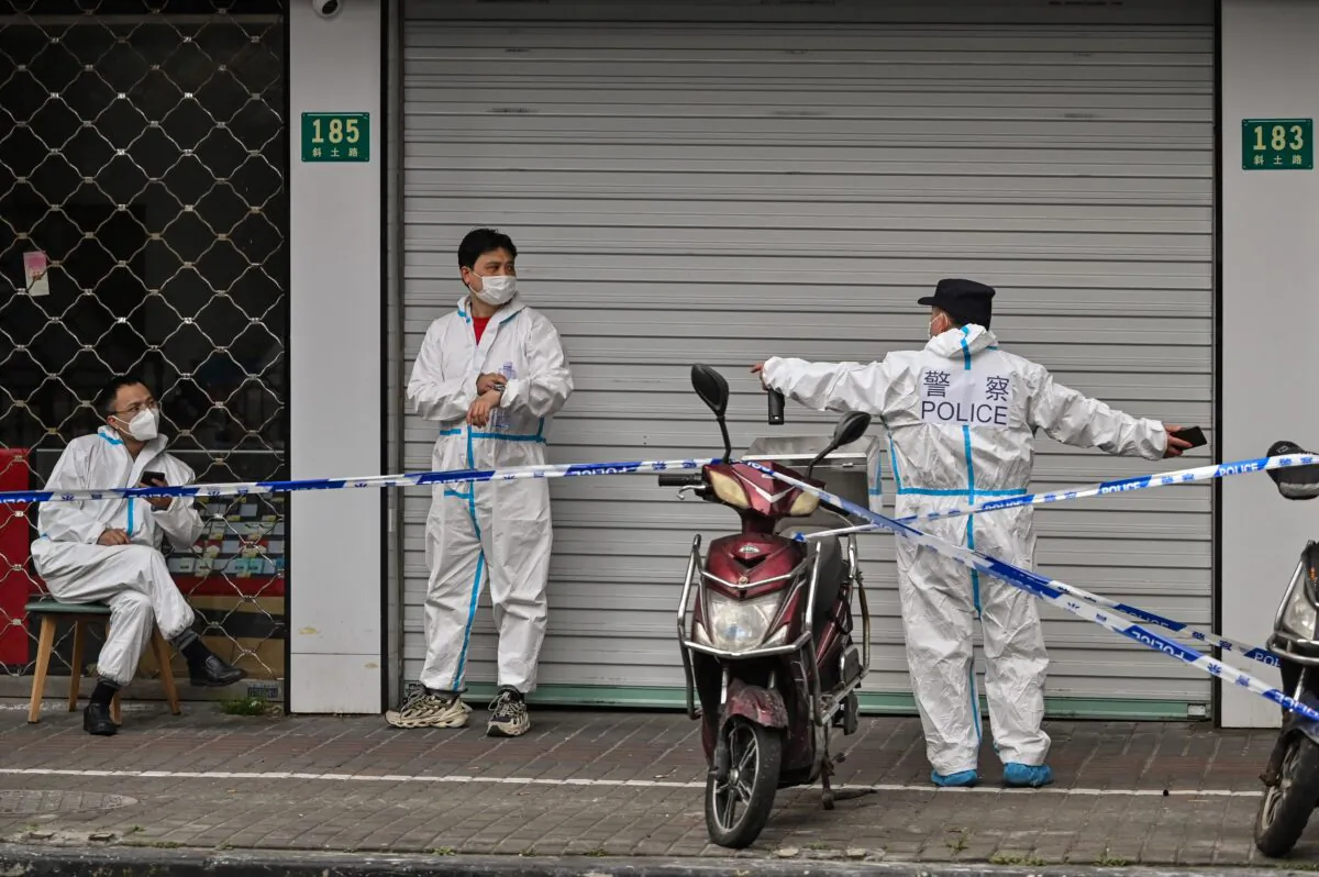 Police and workers in protective gear next to some lockdown areas after the detection of new cases of COVID-19 in Shanghai on March 14, 2022. (Hector Retamal/AFP via Getty Images)