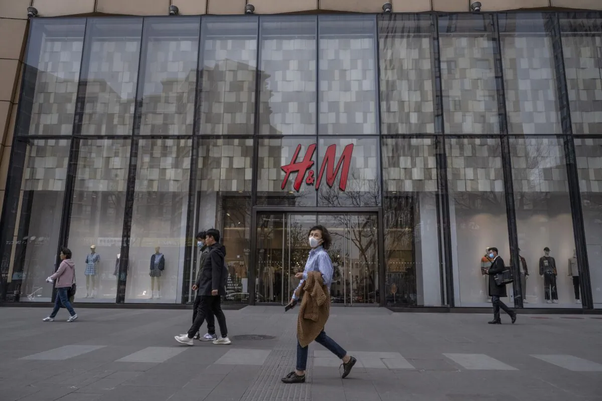 People walk by an H&M clothing store at a shopping area in Beijing, China, on March 30, 2021. Chinese state media and social networking platforms called for boycotts of H&M and removed the retailer from online shopping sites and map apps after statements made by the company in the past about Xinjiang cotton resurfaced online. (Kevin Frayer/Getty Images)