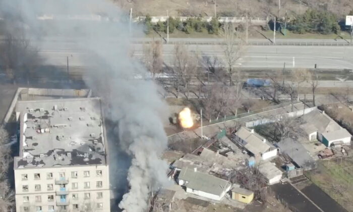 An aeriel view shows smoke rising as an armoured vehicle is shot at next to a building, as Russia's invasion of Ukraine continues, in Mariupol, Ukraine, in this handout drone video obtained by Reuters on March 13, 2022. (Azov Mariupol/Handout via Reuters)