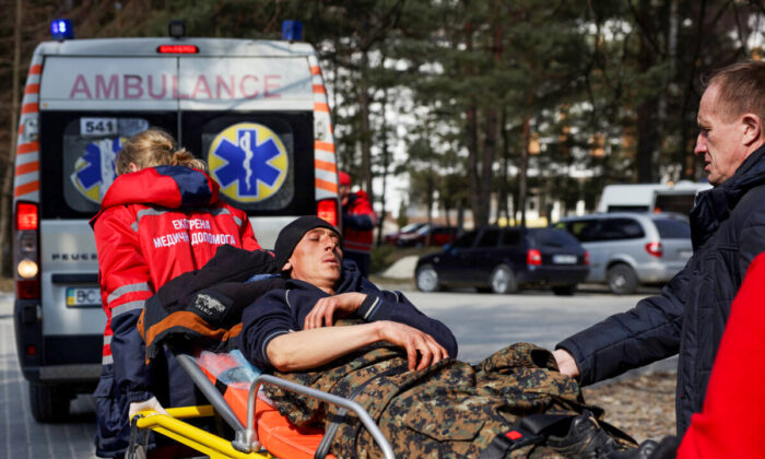 A man wounded in air strikes at a nearby military complex is assisted by medical staff outside Novoiavorivsk District Hospital in Novoiavorivsk, Ukraine, on March 13, 2022. (Dan Kitwood/Getty Images)