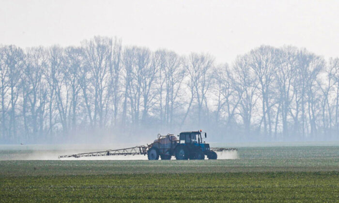 A tractor spreading fertilizers to a field of winter wheat near the village of Husachivka in Kyiv region, Ukraine on April 17, 2020. (Valentyn Ogirenko/Reuters)