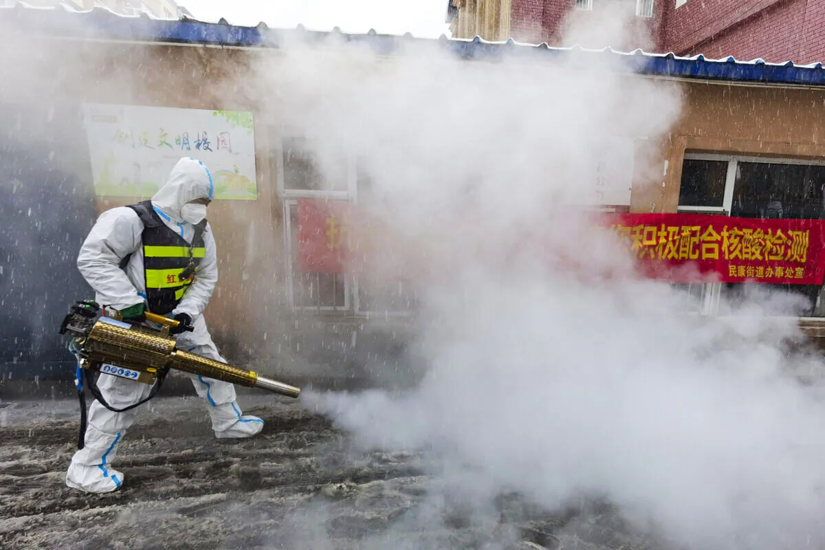A volunteer disinfects the area as it snows during the COVID-19 lockdown in Changchun in northeast China's Jilin province on March 12, 2022. (Chinatopix Via AP)