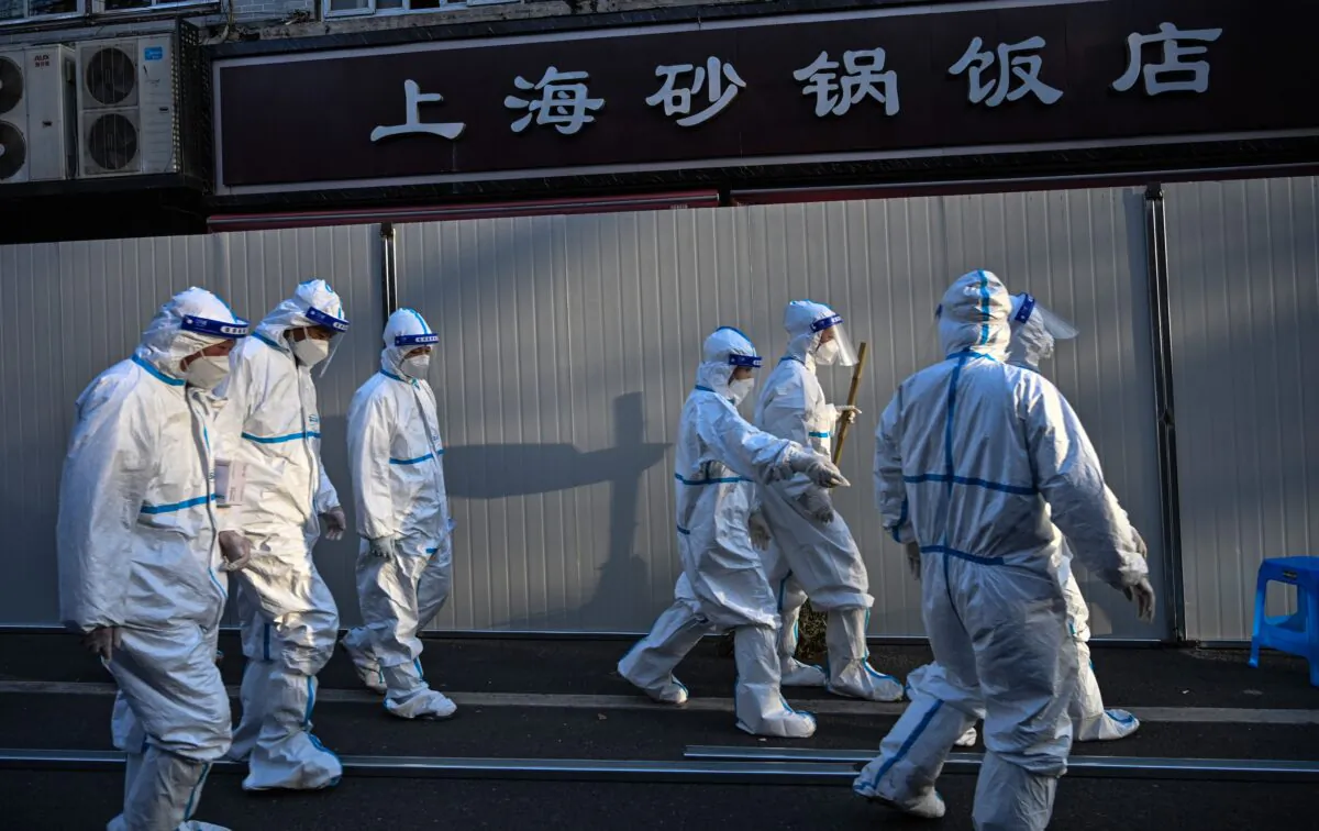 Workers work in wearing protective clothes in an area where barriers are being placed to close off streets around some lockdown areas after the detection of new cases of covid-19 in Shanghai on March 15, 2022. (Hector Retamal/AFP via Getty Images)