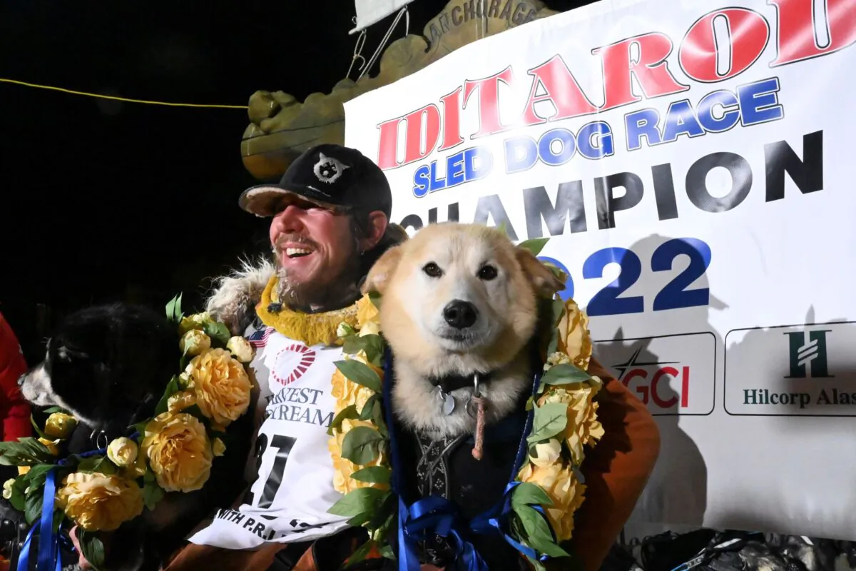 Iditarod winner Brent Sass poses for photos with lead dogs Morello (L) and Slater in the finish chute of the Iditarod Trail Sled Dog Race in Nome, Alaska, on March 15, 2022. (Anne Raup/Anchorage Daily News via AP)