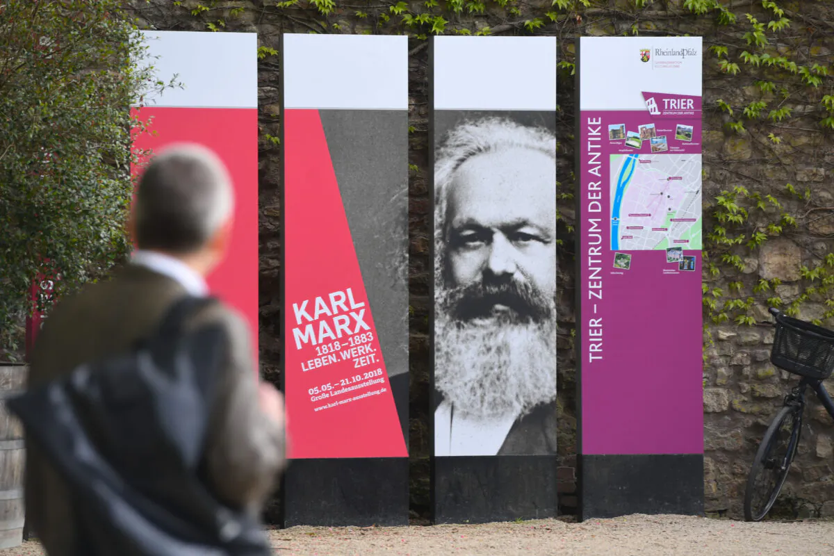 A man walks past boards celebrating 200 years of Karl Marx's birth in Trier, Germany on May 3, 2018. (Photo by Patrik Stollarz/AFP via Getty Images)
