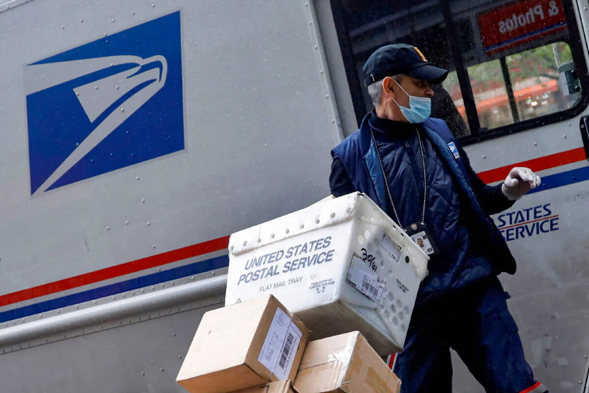 A United States Postal Service (USPS) worker unloads packages from his truck in Manhattan, New York on April 13, 2020. (Mike Segar/Reuters)