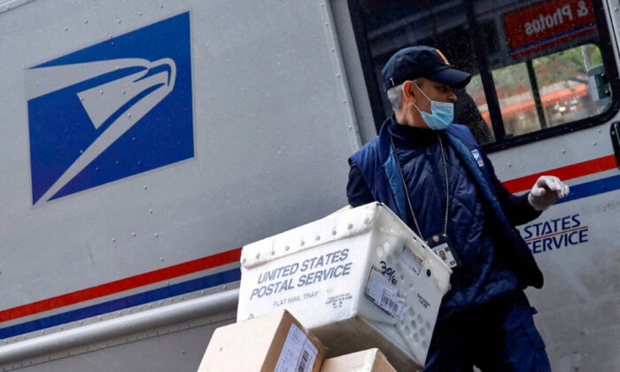 A United States Postal Service (USPS) worker unloads packages from his truck in Manhattan, New York on April 13, 2020. (Mike Segar/Reuters)