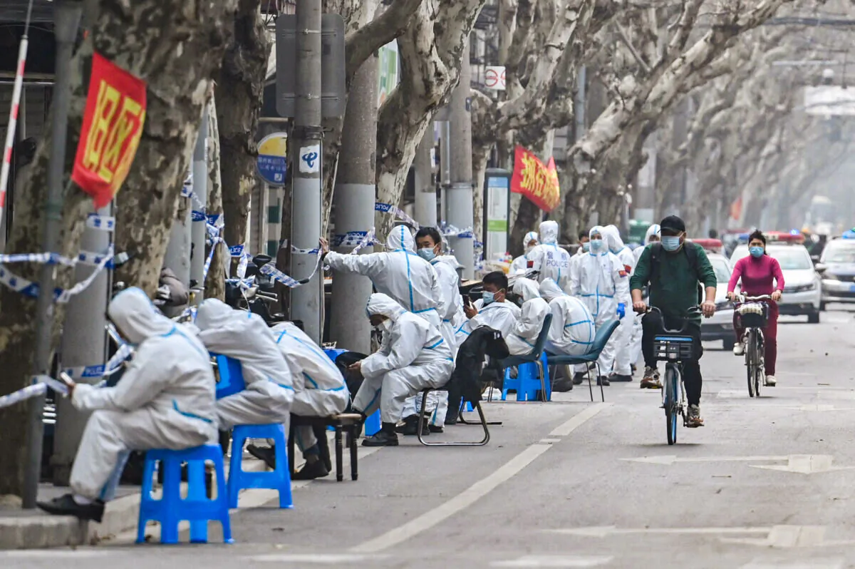 Workers are seen wearing protective clothes next to some lockdown areas after the detection of new cases of covid-19 in Shanghai on March 14, 2022. (Hector Retamal/AFP via Getty Images)