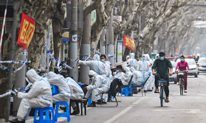 Workers are seen wearing protective clothes next to some lockdown areas after the detection of new cases of covid-19 in Shanghai on March 14, 2022. (Hector Retamal/AFP via Getty Images)