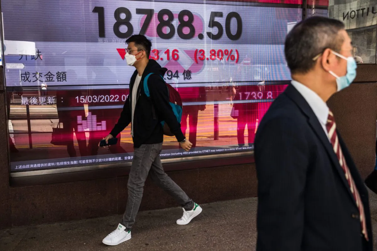 A man walks past a display showing the Hang Seng Index in Hong Kong on March 15, 2022. (Dale de la Rey/AFP via Getty Images)