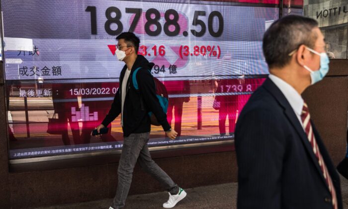 A man walks past a display showing the Hang Seng Index in Hong Kong on March 15, 2022. (Dale de la Rey/AFP via Getty Images)