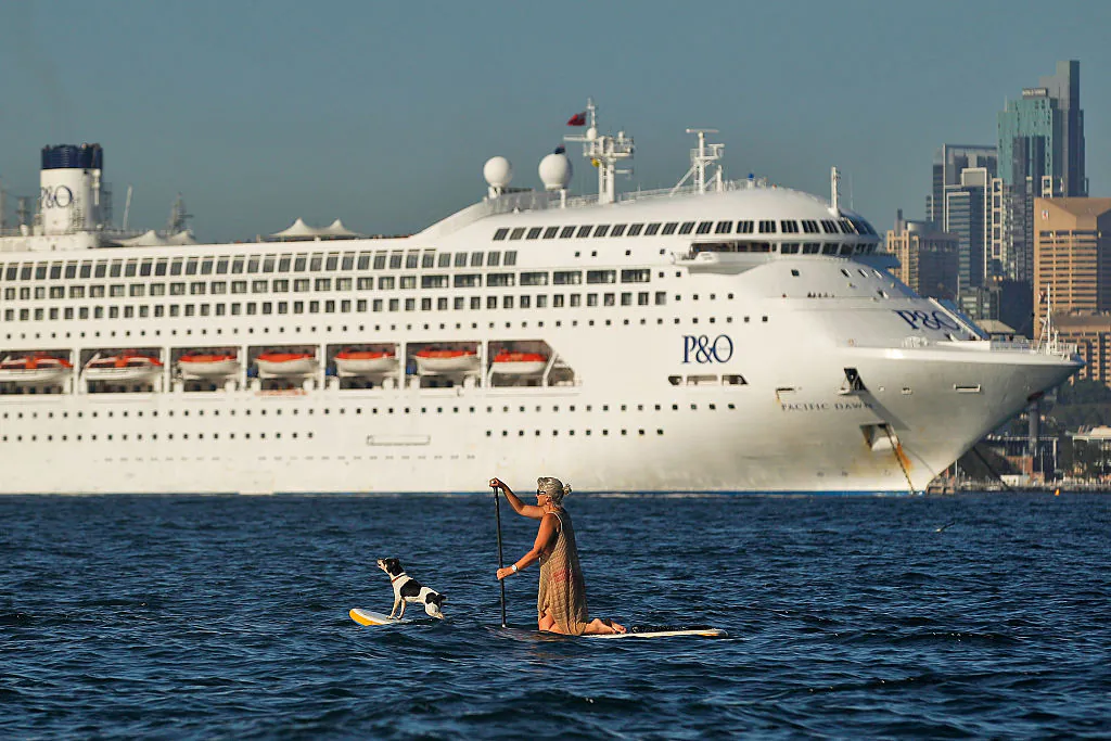 A woman paddle boards with her dog as P&O's Pacific Dawn is moored in Sydney Harbour in Sydney, Australia on November 25, 2015 . (Photo by Brendon Thorne/Getty Images)