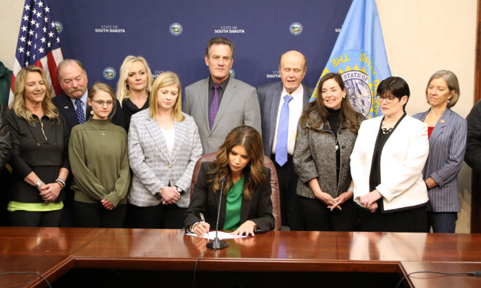 South Dakota Gov. Kristi Noem signs a bill into law banning outside spending on elections, in Pierre, S.D., on March 16, 2022. (Courtesy of the Office of the South Dakota Governor)