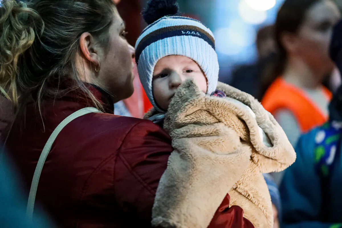 A mother and child wait at the Lviv train station in western Ukraine, on March 16, 2022. (Charlotte Cuthbertson/The Epoch Times)