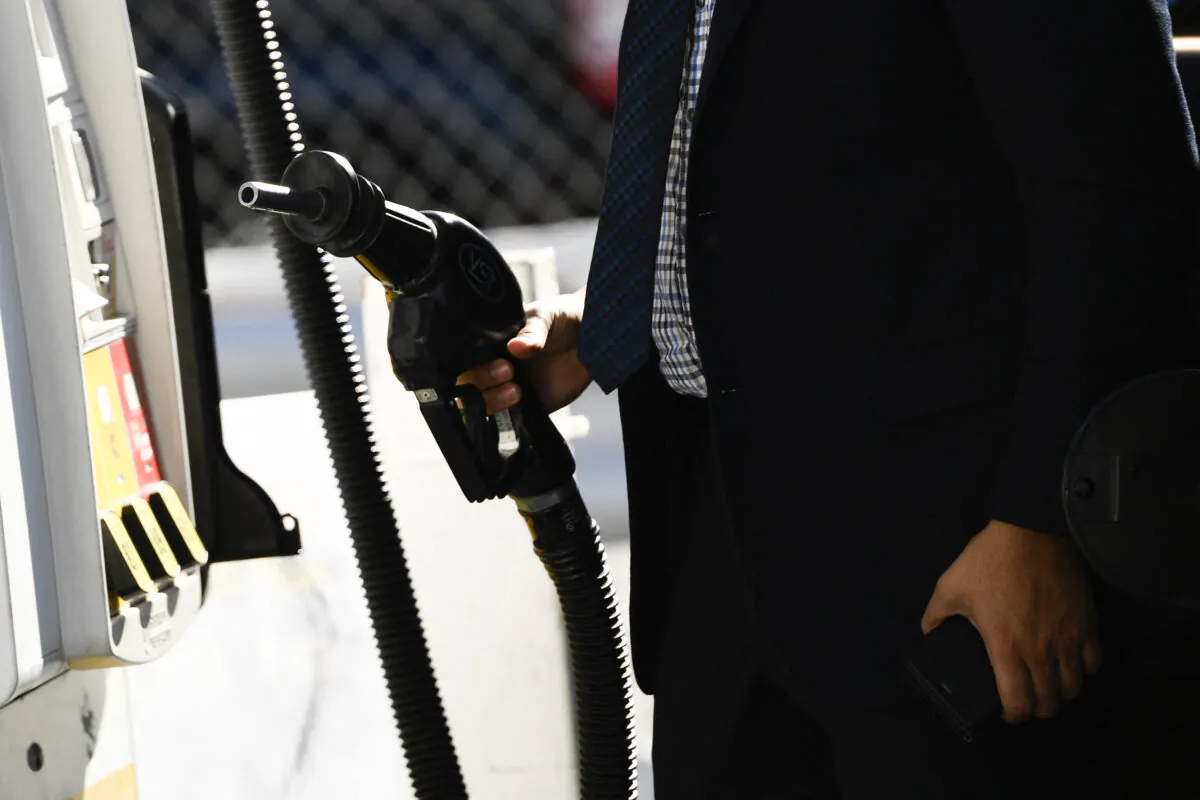 A customer returns a nozzle to a pump after fueling gasoline into a sport utility vehicle (SUV) at a Shell gas station in the Chinatown neighborhood of Los Angeles on Feb. 17, 2022. (Patrick T. Fallon/AFP via Getty Images)