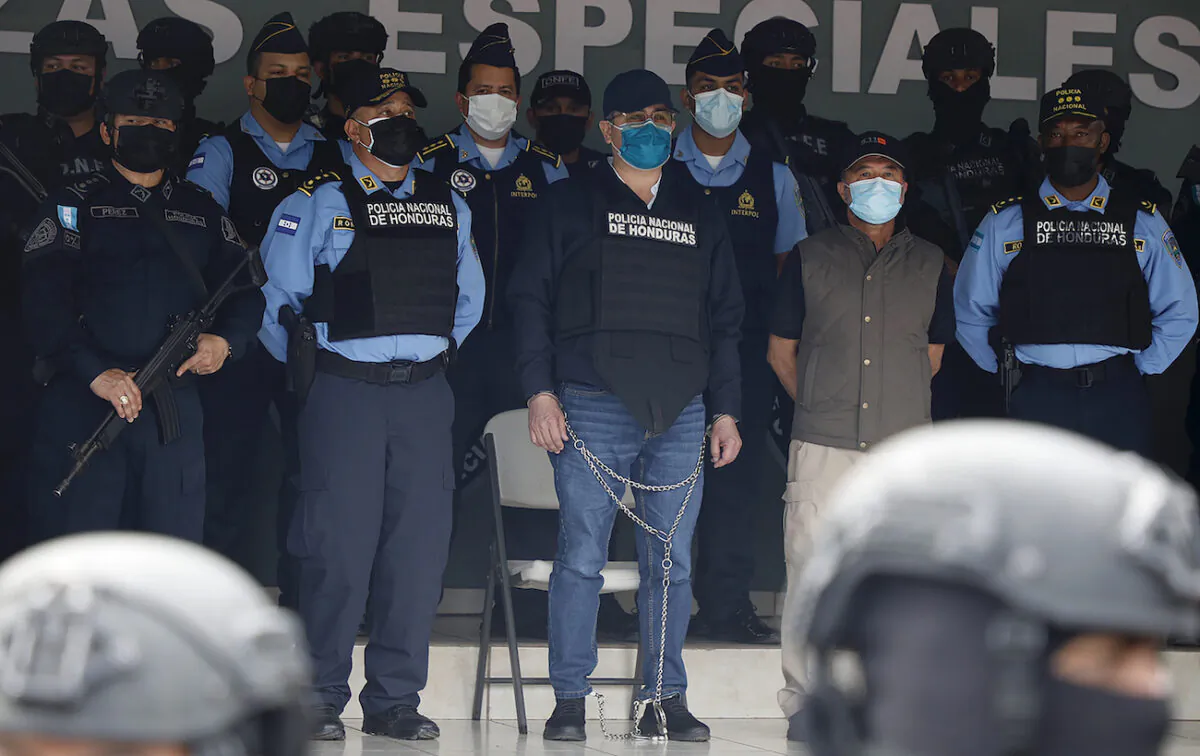 Former Honduran President Juan Orlando Hernandez, center in chains, is shown to the press at the Police Headquarters in Tegucigalpa, Honduras, on Feb. 15, 2022. (AP Photo/Elmer Martinez)