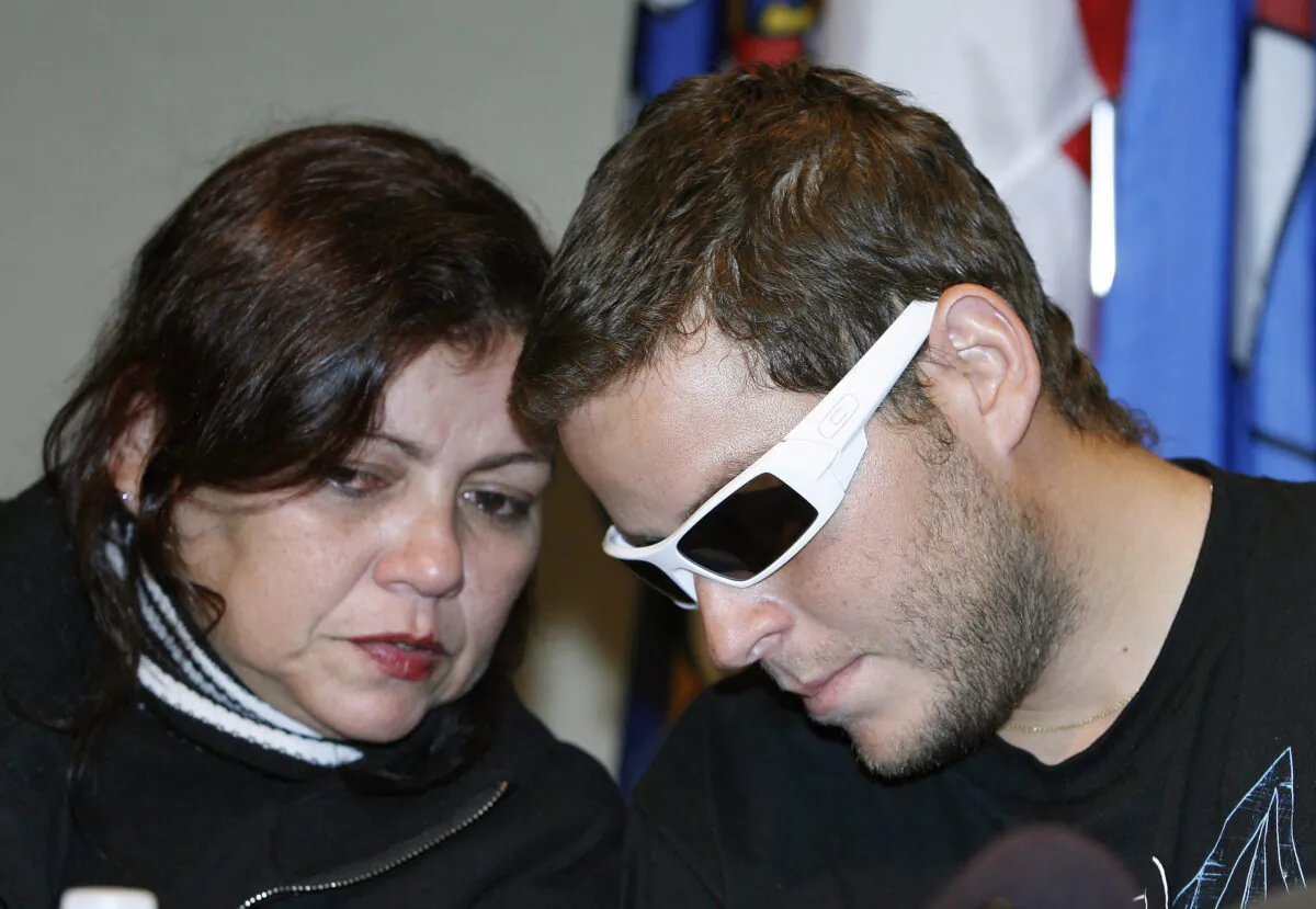 Brazilian student Jose Neto (right) leans over to his mother Teresa Ribeiro (left) as he speaks at a press conference in Calgary, Alberta on Sept. 26 2008 about a shooting that left him totally blind. (The Canadian Press/Larry MacDougal)