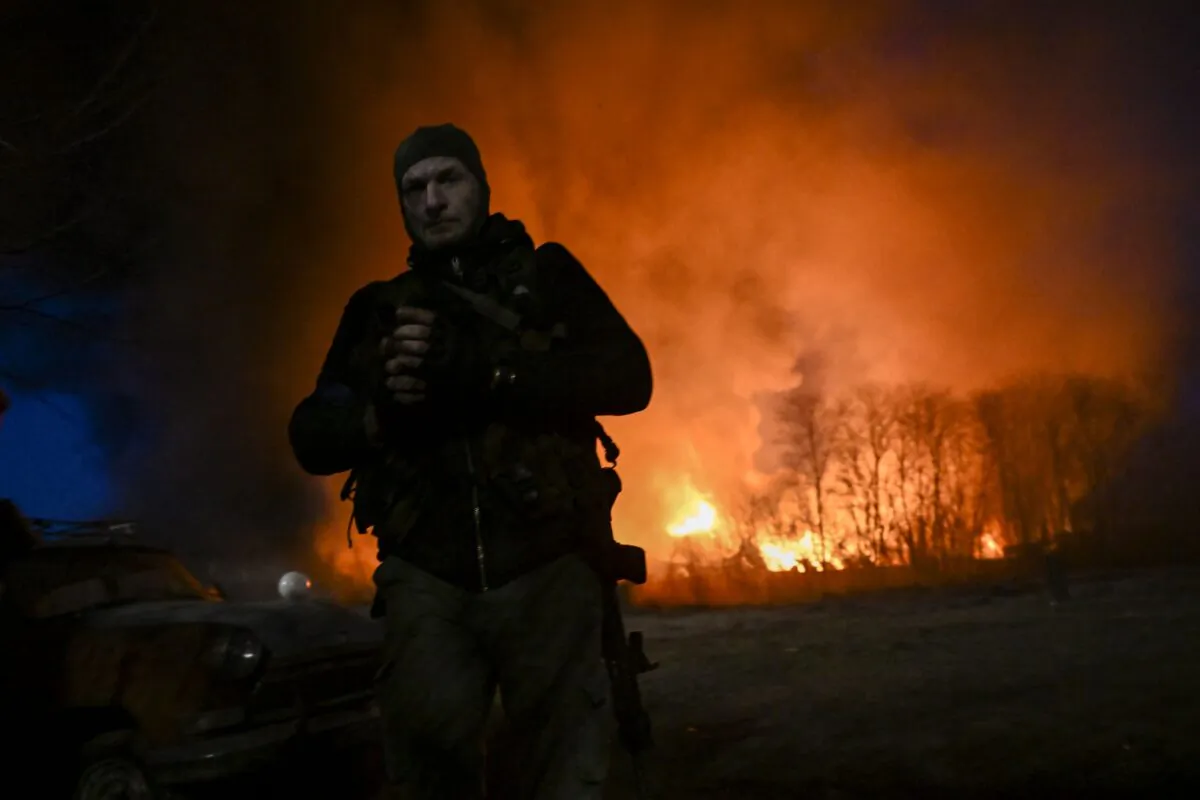 A Ukrainian serviceman looks on as he stands in front of a burning warehouse after a shelling in Kyiv on March 17, 2022. (Aris Messinis/AFP via Getty Images)