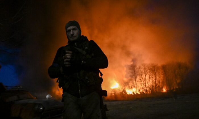 A Ukrainian serviceman looks on as he stands in front of a burning warehouse after a shelling in Kyiv on March 17, 2022. (Aris Messinis/AFP via Getty Images)