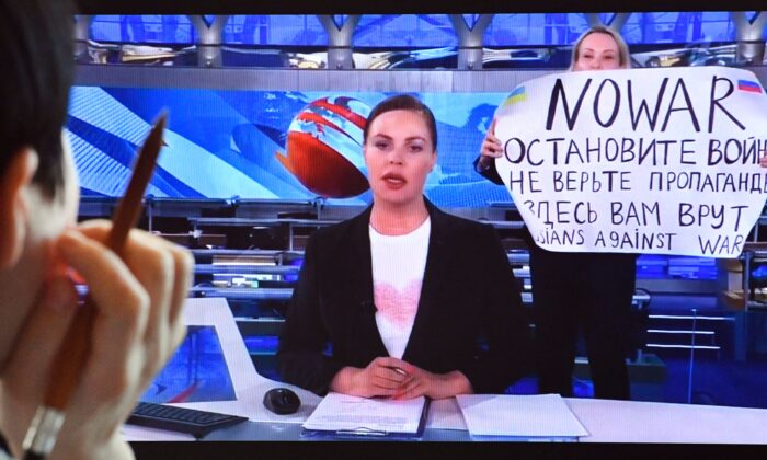 An image of Russian Channel One employee Marina Ovsyannikova entering Ostankino on-air TV studio in Moscow during Russia's most-watched evening news broadcast on March 14, holding up a poster that reads as "No War" and condemning Moscow's military action in Ukraine, taken on March 15, 2022. (AFP via Getty Images)