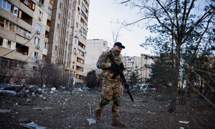 A member of the Ukrainian military surveys an area next to a residential building that was hit by an intercepted missile, in Kyiv, Ukraine, on March 17, 2022. (Thomas Peter/Reuters)