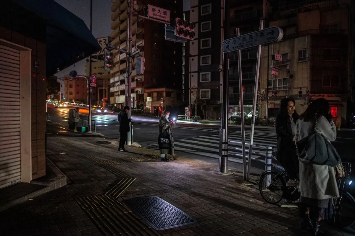 After a powerful 7.3-magnitude quake jolted east Japan, people stay along a street of a residential area during a power outage in Koto district in Tokyo early on March 17, 2022. (Philip Fong/AFP via Getty Images)