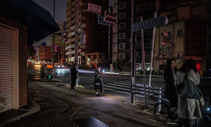 After a powerful 7.3-magnitude quake jolted east Japan, people stay along a street of a residential area during a power outage in Koto district in Tokyo early on March 17, 2022. (Philip Fong/AFP via Getty Images)