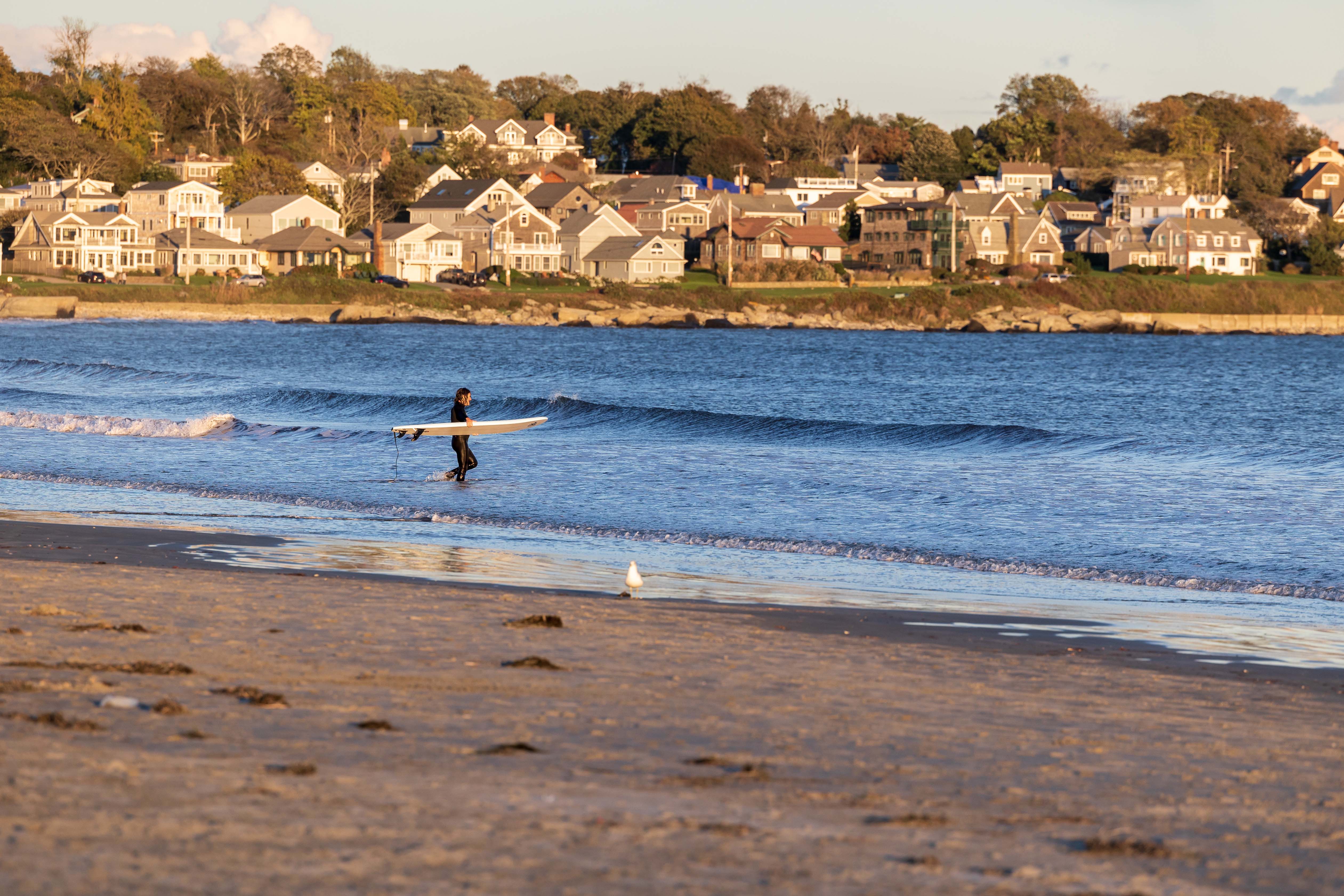 Surfer walking out into the water on Easton's Beach, Newport