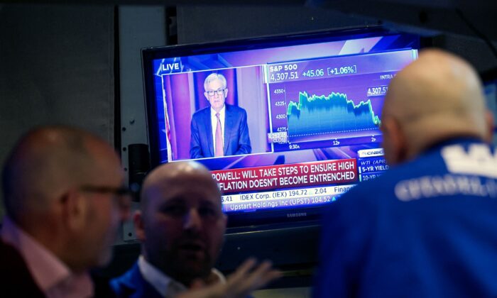 Traders work as Federal Reserve Chair Jerome Powell is seen on a screen delivering remarks at the New York Stock Exchange in New York City on March 16, 2022. (Brendan McDermid/Reuters)