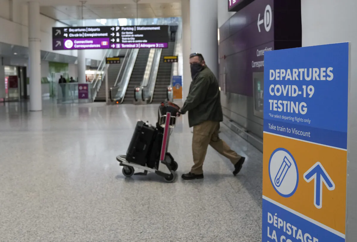 A traveller walks past a departures COVID-19 testing sign at Pearson International Airport on Dec. 3, 2021. (Nathan Denette/The Canadian Press)