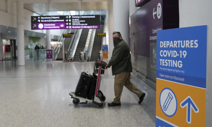 A traveller passing a departures COVID-19 testing sign at Pearson International Airport on Dec. 3, 2021. (Nathan Denette/The Canadian Press)