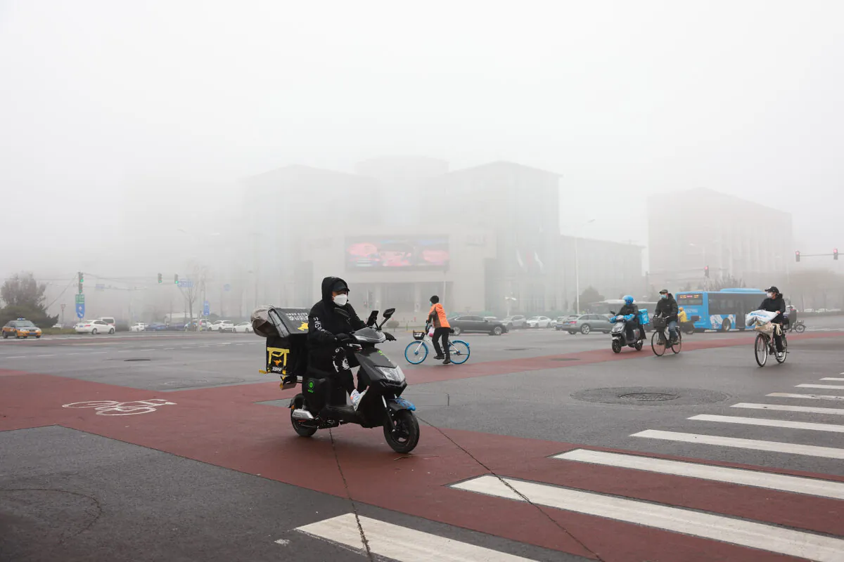 People wear masks as they travel on a street during smoggy weather in Beijing on Nov. 18, 2021. China, the largest contributor to carbon emissions, has plans to peak them by 2030, and to become carbon neutral by 2060. (Lintao Zhang/Getty Images)
