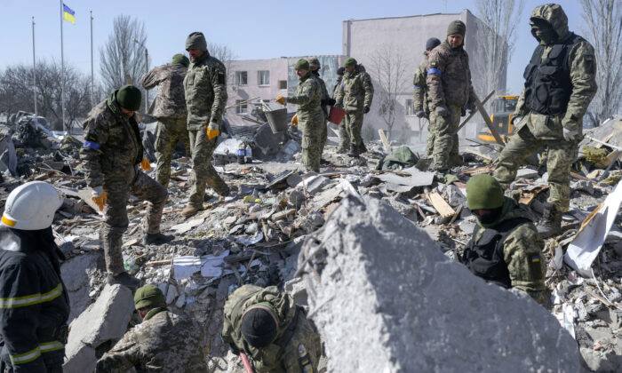 Ukrainian soldiers search for bodies in the debris at the military school hit by Russian rockets the day before, in Mykolaiv, southern Ukraine, on March 19, 2022. (Bulent Kilic/AFP via Getty Images)