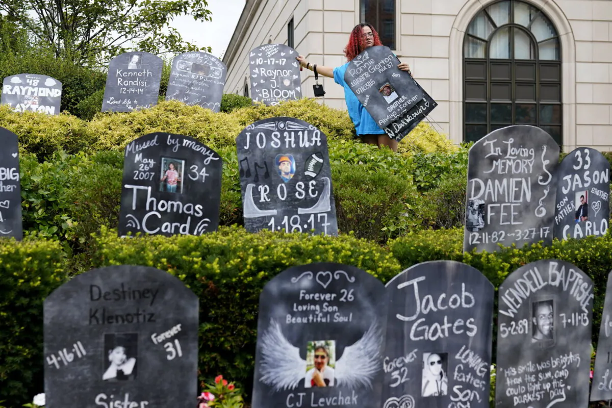 Jayde Newton helps to set up cardboard gravestones with the names of victims of opioid abuse outside the courthouse where the Purdue Pharma bankruptcy is taking place in White Plains, N.Y., on Aug. 9, 2021. (Seth Wenig/AP Photo