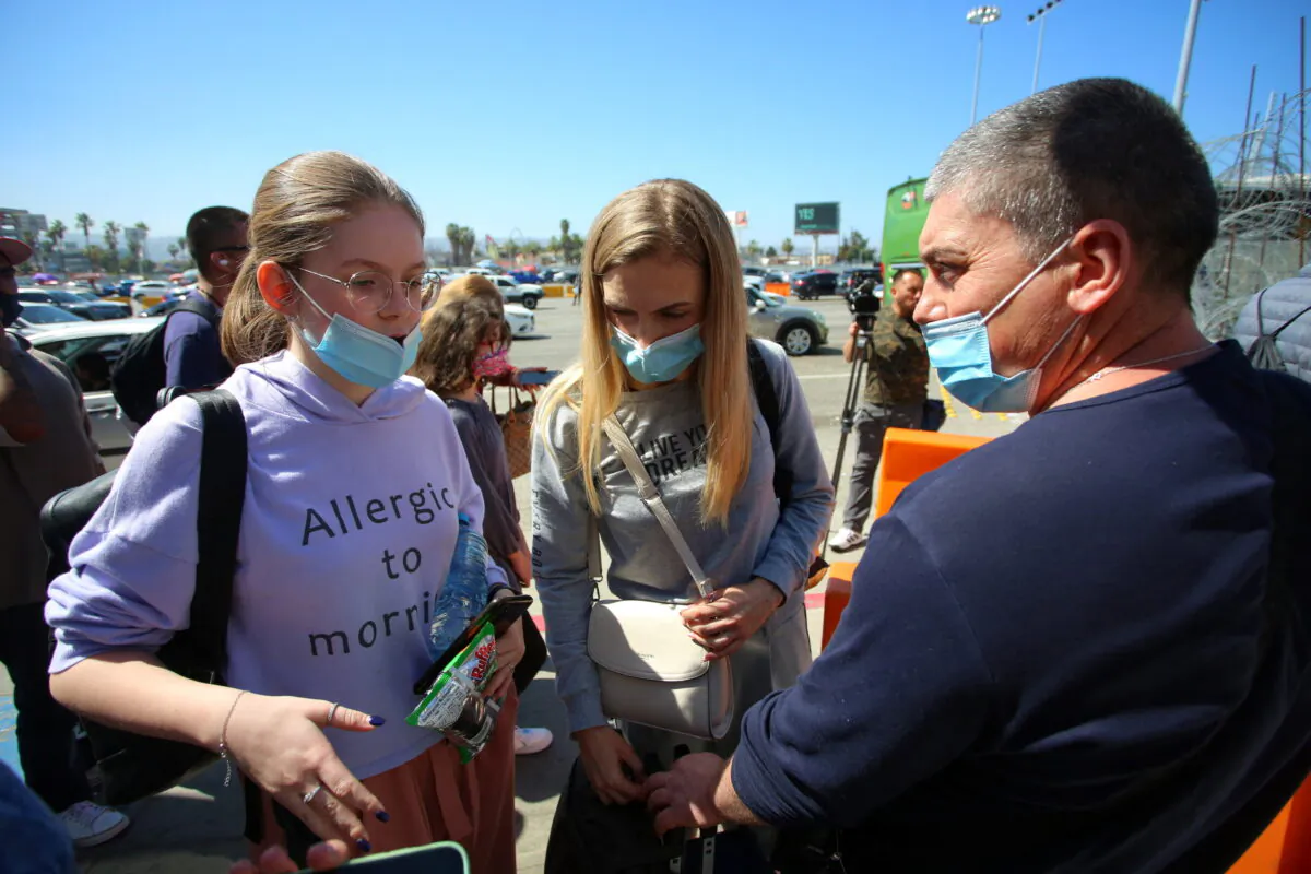 A Ukrainian family chat as they wait for a humanitarian visa at the San Ysidro Port of Entry on the U.S.-Mexico border in Tijuana, on March 15, 2022. (Jorge Duenes/Reuters)