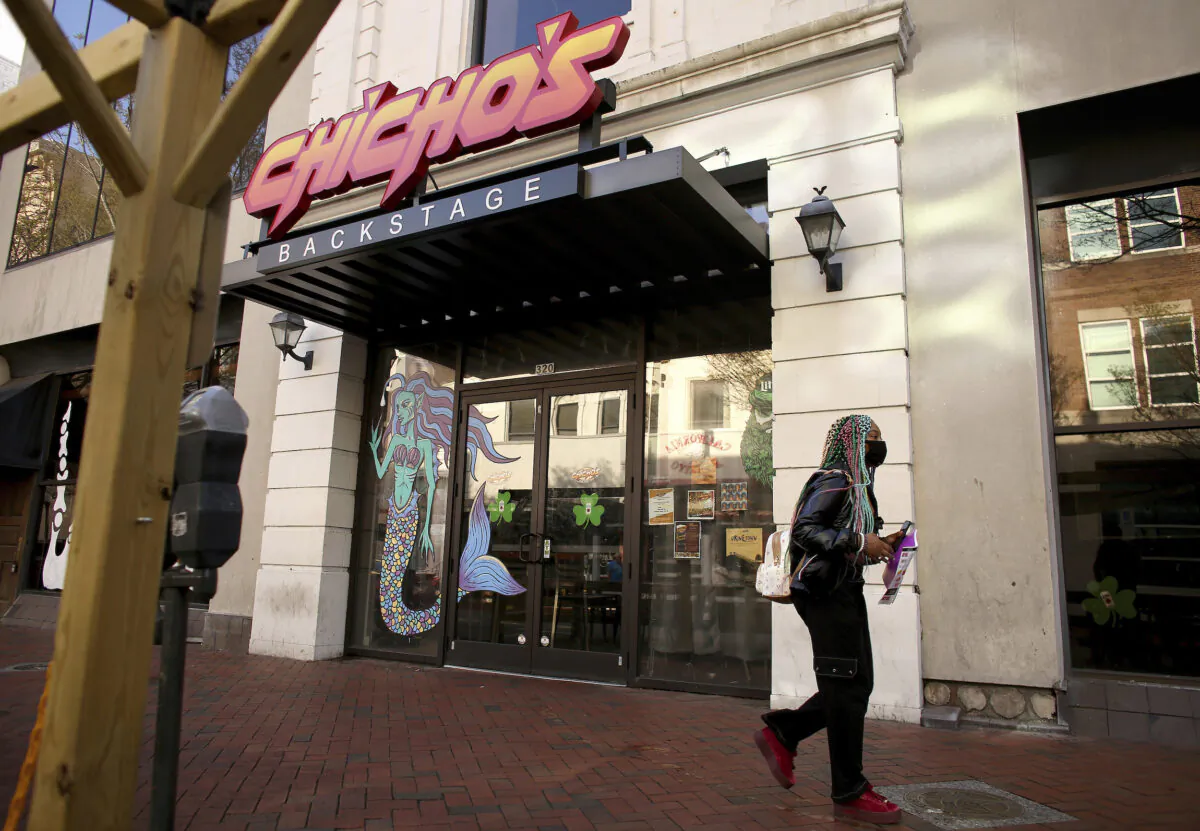 A person walks by Chicho’s Pizza Backstage where a fatal shooting took place outside the restaurant and bar earlier in the day, in Norfolk, Va., on March 19, 2022. (Stephen M. Katz/The Virginian-Pilot via AP)