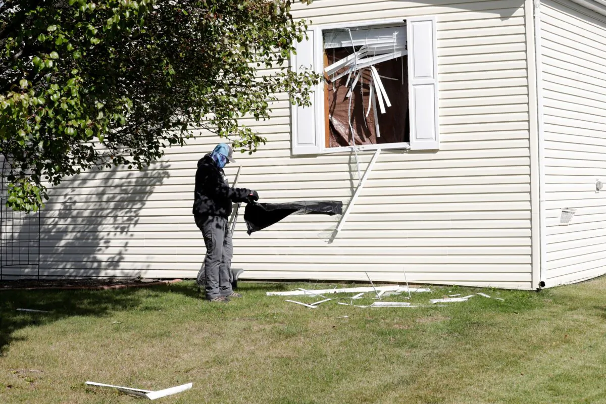 A person cleans up debris from a broken window at a home FBI agents searched in Hartland Township mobile home park late Wednesday night and into Thursday morning in connection of a plot to kidnap Michigan Governor Gretchen Whitmer, on Oct. 8, 2020 in Heartland, Michigan. (JEFF KOWALSKY/AFP via Getty Images)