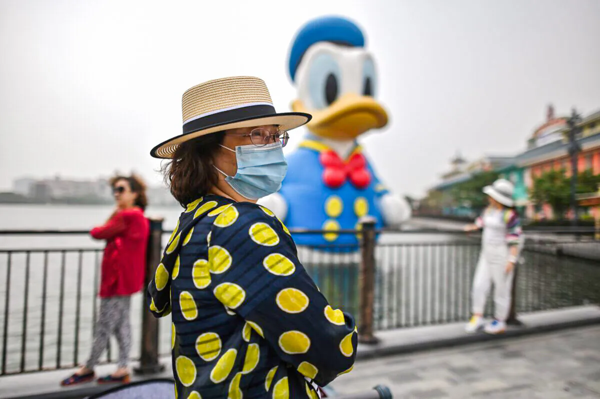 A woman wearing a face mask visits Disney Town in Shanghai on May 11, 2020. Disneyland Shanghai reopened on May 11 to the public after being closed since January 2020 due to the COVID-19 coronavirus outbreak. (HECTOR RETAMAL/AFP via Getty Images)