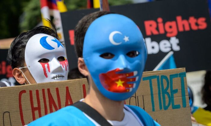 Tibetan and Uyghur activists wear masks during a protest against Beijing 2022 Winter Olympics in front of the Olympics Museum in Lausanne on June 23, 2021 as some 200 participants took part to the protest. (Photo by Fabrice COFFRINI / AFP) 