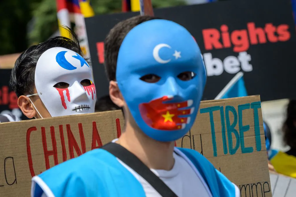 Uyghur activists wear masks during a protest against Beijing 2022 Winter Olympics in front of the Olympics Museum in Lausanne on June 23, 2021 as some 200 participants took part to the protest. (Fabrice COFFRINI / AFP) 