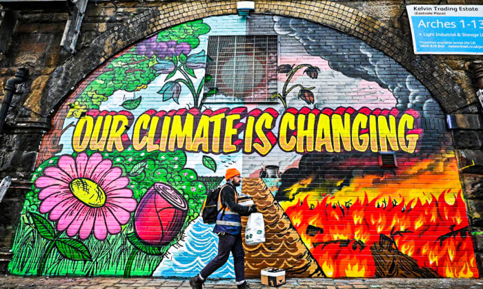 Artists paint a mural on a a wall next to the Clydeside Expressway near Scottish Events Centre (SEC) which will be hosting the COP26 U.N. Climate Summit in Glasgow, Scotland, on Oct. 13, 2021. (Jeff J Mitchell/Getty Images)