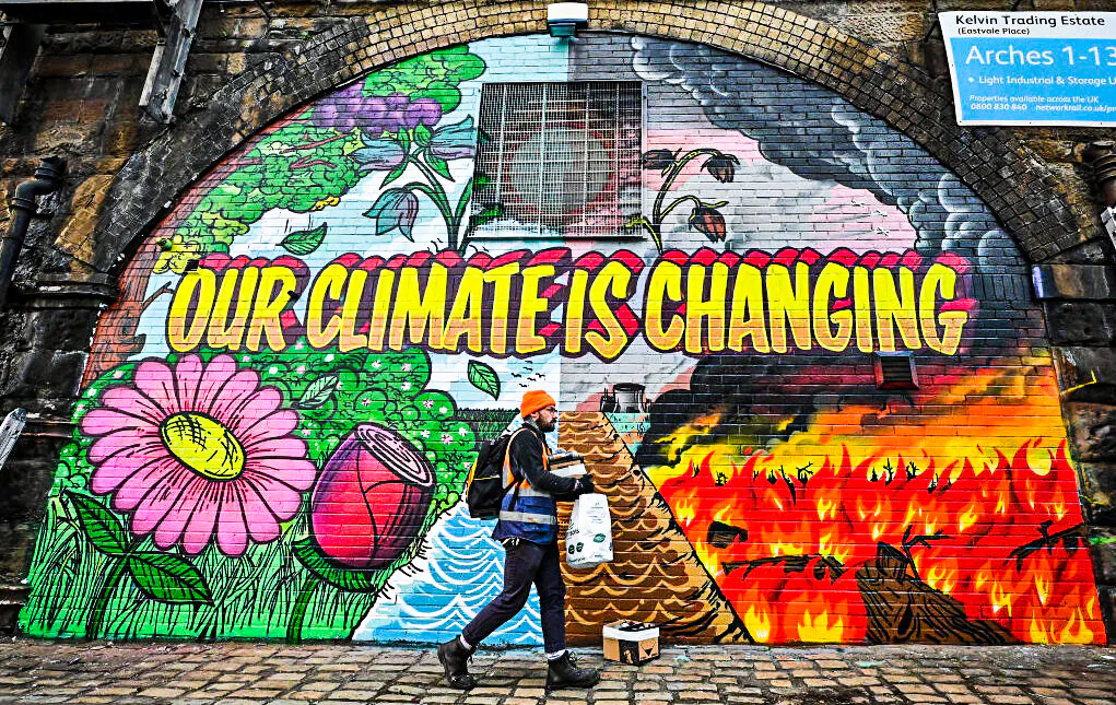 Artists paint a mural on a a wall next to the Clydeside Expressway near Scottish Events Centre (SEC) which will be hosting the COP26 U.N. Climate Summit in Glasgow, Scotland, on Oct. 13, 2021. (Jeff J Mitchell/Getty Images)